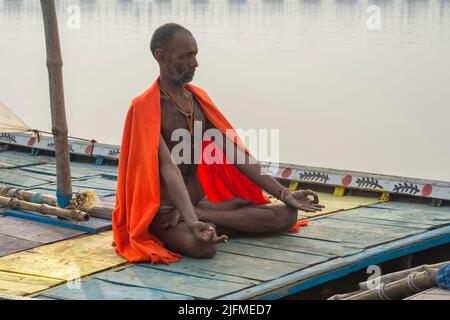 Sadhu mit rotem Schal auf einer Bootsfahrt auf dem Ganges bei Sonnenaufgang, Allahabad Kumbh Mela, der weltweit größte religiöse Versammlung, Uttar Pradesh, Indien Stockfoto