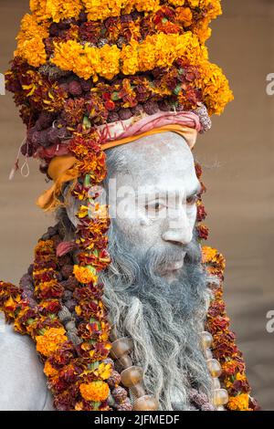 Weiße Asche bedeckt Sadhu mit einem Hut aus Ringelblume Girlande Halsketten, nur für redaktionelle Verwendung, Allahabad Kumbh Mela, der weltweit größte religiöse Sammler Stockfoto