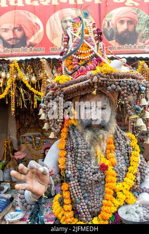 Weiße Asche bedeckt Sadhu mit einem Hut mit Ringelblume Girlande Halsketten und Perlen, nur für redaktionelle Verwendung, Allahabad Kumbh Mela, weltweit größte Stockfoto