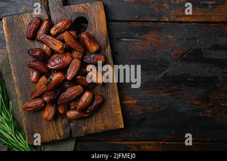 Getrocknete Dattelpalmfrüchte, auf altem dunklen Holztischhintergrund, Draufsicht flach liegend, mit Platz für Text Stockfoto