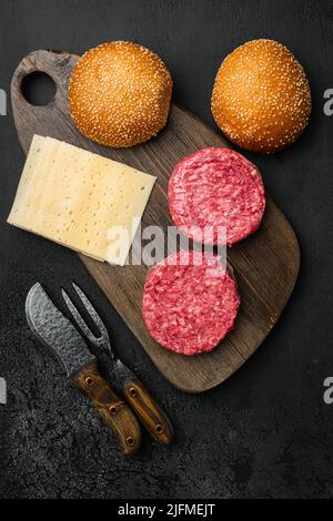 Roh Hackfleisch Burger-Patties auf schwarzem dunklen Stein Tischhintergrund, Draufsicht flach liegend Stockfoto