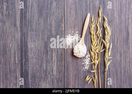 Haferflocken und Haferohren auf einem Holztisch, mit Kopieplatz. Ähren aus Weizen auf dem Tisch. Stockfoto