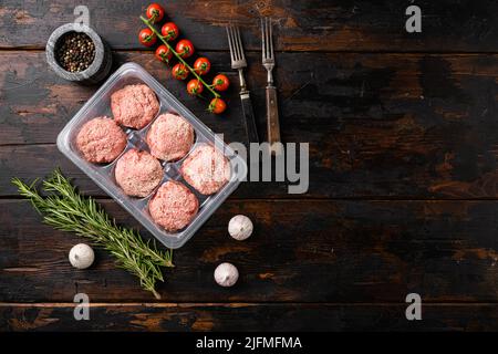 Rohe frische Hühnerschnitzel in durchsichtigem Plastikbehälter, auf altem dunklen Holztischhintergrund, Draufsicht flach liegend, mit Platz für Text Stockfoto