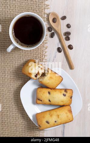 Tasse Kaffee und Kuchen mit Schokoladenstückchen auf Holztisch, Draufsicht Stockfoto