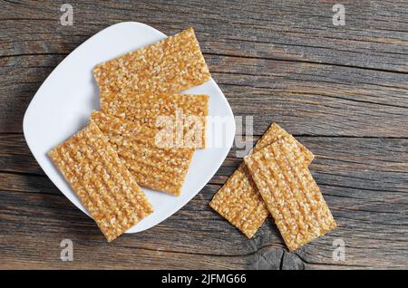 Sesamstangen mit Honig in Teller auf altem Holztisch, Draufsicht. Gesunde Ernährung Stockfoto