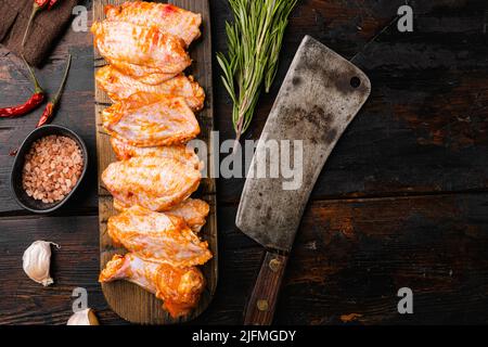 Rohe marinierte Hähnchenflügel mit Gewürzen, auf altem dunklen Holztischhintergrund, Draufsicht flach liegend, mit Platz für Text Stockfoto