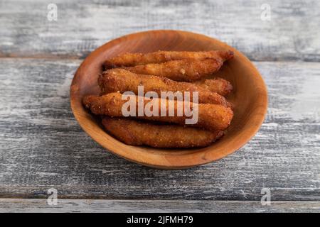 Hühnchen-Nuggets auf einem Holzteller auf einem grauen Holzhintergrund. Seitenansicht, Nahaufnahme. Stockfoto
