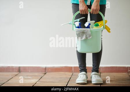 Nahaufnahme eines Reinigungsarbeiters, der Eimer mit verschiedenen Vorräten für die Hausarbeit hält Stockfoto