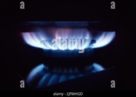 Blaue Flamme des Hausgases auf einem Küchenherd auf schwarzem Hintergrund Stockfoto
