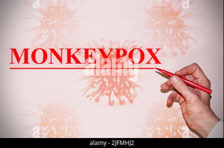 Hand eines Arztes, der das Wort „Monkeypox“ mit der Bakterienzelle als Hintergrund schreibt. Konzept des Virus. Stockfoto