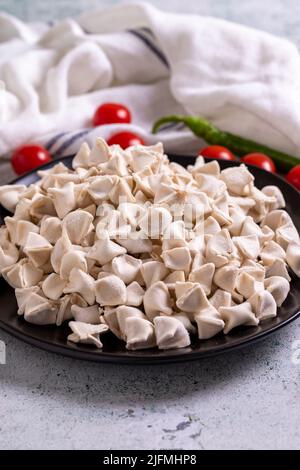 Gefrorene Ravioli auf Steinboden. Gefüllte Ravioli in der Mitte. Türkische Ravioli. Traditionelle Köstlichkeiten der Weltküche. Nahaufnahme. Stockfoto