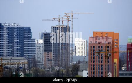 Kiew, Ukraine 13. April 2020: Hochhaus-Krane auf dem Hintergrund von Häusern am linken Ufer der Stadt Kiew Stockfoto