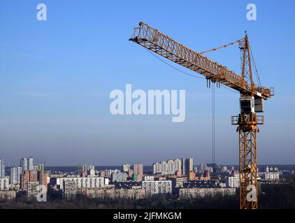 Hohe Baukräne auf dem Hintergrund der Häuser am linken Ufer der Stadt Kiew Stockfoto