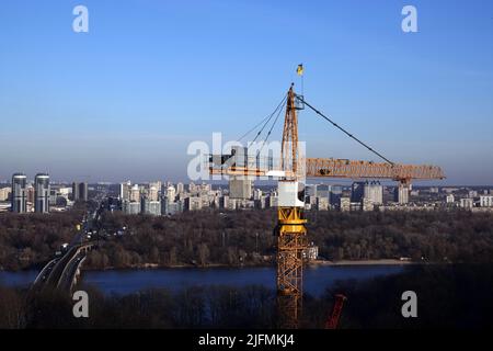 Hohe Baukräne auf dem Hintergrund der Häuser am linken Ufer der Stadt Kiew Stockfoto