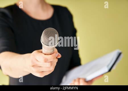 Journalist mit Mikrofon interviewst Sie. Zugeschnittenes Bild einer Reporterin, die das Mikrofon an die Kamera hält, Fokus auf das Mikrofon. Journalismus, Ausstrahlung Stockfoto