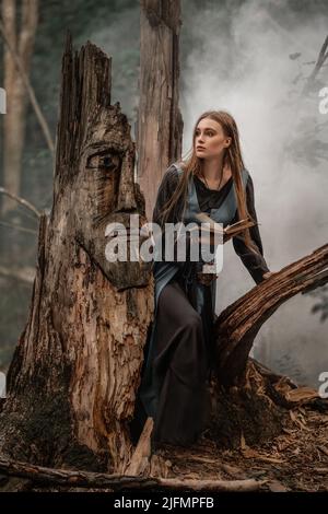 Eine geheimnisvolle Hexe geht in einem dunklen Wald Stockfoto