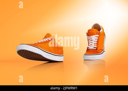 Moderne Unisex-Schuhe, Sneakers isoliert auf orangefarbenem Hintergrund. Modische, modische Sport-Freizeitschuhe. Kreatives, minimalistisches Layout mit Schuhen. Stockfoto