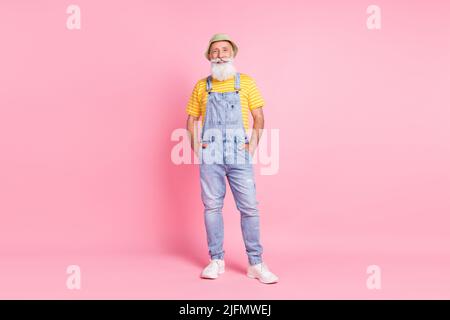 In voller Länge Körpergröße Ansicht der attraktiven fröhlich bärtigen Mann hält Hände in Taschen isoliert über rosa Pastellfarben Hintergrund Stockfoto