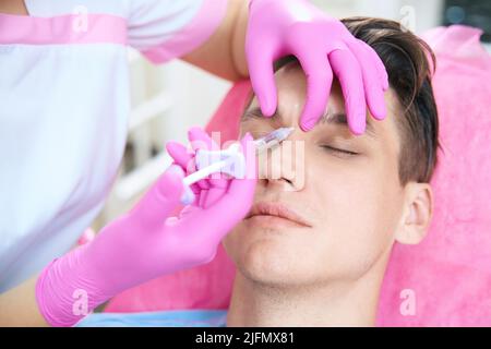 Junger Mann erhält Botox-Injektionen in Beaty-Klinik Stockfoto