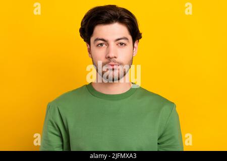 Foto von jungen ernst charmanten Mann tragen grünen Pullover lässig isoliert auf glänzendes Gelb Farbe Hintergrund Stockfoto