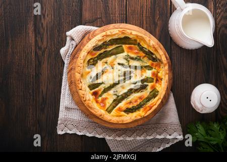 Quiche. Hausgemachter Spargelkuchen oder Quiche mit Käse und Spinat auf altem dunklen Holztisch Hintergrund. Draufsicht. Stockfoto