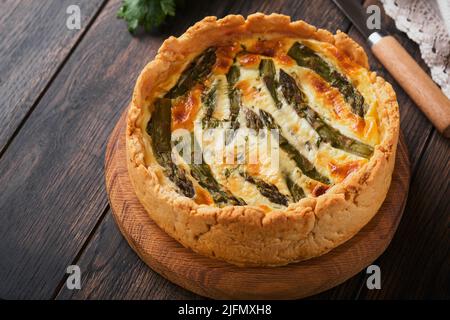 Quiche. Hausgemachter Spargelkuchen oder Quiche mit Käse und Spinat auf altem dunklen Holztisch Hintergrund. Draufsicht. Stockfoto