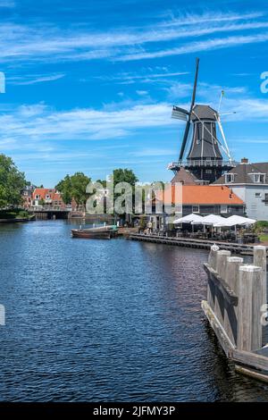 Der ikonische Blick auf Holland mit der Windmühle De Adriaan. Plus Kanalseite Leben in der schönen Stadt Haarlem, westlich von Amsterdam, Niederlande. Stockfoto