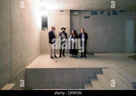 Potsdam, Deutschland. 04.. Juli 2022. Architekt Jost Haberland (l-r), Potsdamer Rabbiner David Gewirtz, Manja Schüle (SPD), Brandenburgs Ministerin für Wissenschaft, Forschung und Kultur und der Brandenburgische Finanzminister Frank Stolper stehen bei einem Rundgang durch die Baustelle der Synagoge im Untergeschoss hinter dem Mikveh-Becken (Jüdisches Tauchbad). Neben Gebetsräumen wird das neue Zentrum auch einen Veranstaltungsraum und das Besuchercafé sowie Gemeinschafts- und Büroräume beherbergen. Quelle: Soeren Stache/dpa/Alamy Live News Stockfoto