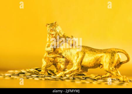 Bär und Stier kämpfen um Bitcoins vor goldenem Hintergrund. Markttrend-Konzept. Stockfoto