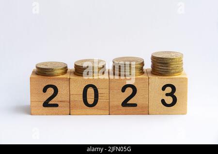 Neujahr 2023 Text auf Holzblöcken mit Goldmünzen oben. Konzept für das neue Jahr Stockfoto