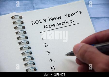 2023 Neujahrsvorsätze Text auf Notizblock mit der Hand, die einen Stift hält. Lösungskonzept für das neue Jahr und Platz für Kopien Stockfoto