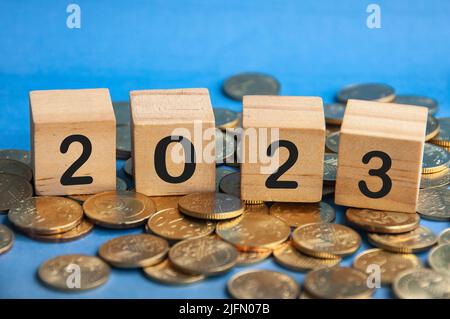 Text zum neuen Jahr 2023 auf Holzblöcken auf Goldmünzen. Konzept für das neue Jahr Stockfoto