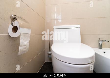 Nahaufnahme von Toilettenschüssel, Toilettenpapier, Bidet in einem modernen Badezimmer Stockfoto