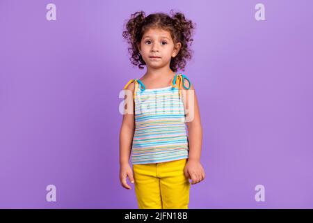 Foto von schönen kleinen Brünette Mädchen tragen gestreiften Top isoliert auf violettem Hintergrund Stockfoto