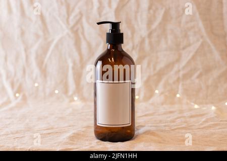 Leere bernsteinfarbene Glasseife oder Shampoo-Flasche auf isoliertem Hintergrund. Hautpflege oder Haarkonzept mit Naturkosmetik. Stockfoto