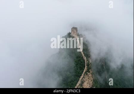 Peking, China. 4.. Juli 2022. Luftaufnahme vom 4. Juli 2022 zeigt Wolken, die über der Großen Mauer im Grenzgebiet zwischen dem Luanping Bezirk in der nordchinesischen Provinz Hebei und dem Miyun Bezirk in Peking, der Hauptstadt Chinas, schweben. Quelle: Chen Yehua/Xinhua/Alamy Live News Stockfoto