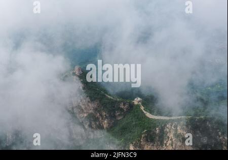 Peking, China. 4.. Juli 2022. Luftaufnahme vom 4. Juli 2022 zeigt Wolken, die über der Großen Mauer im Grenzgebiet zwischen dem Luanping Bezirk in der nordchinesischen Provinz Hebei und dem Miyun Bezirk in Peking, der Hauptstadt Chinas, schweben. Quelle: Chen Yehua/Xinhua/Alamy Live News Stockfoto