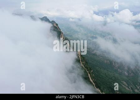 Peking, China. 4.. Juli 2022. Luftaufnahme vom 4. Juli 2022 zeigt Wolken, die über der Großen Mauer im Grenzgebiet zwischen dem Luanping Bezirk in der nordchinesischen Provinz Hebei und dem Miyun Bezirk in Peking, der Hauptstadt Chinas, schweben. Quelle: Chen Yehua/Xinhua/Alamy Live News Stockfoto