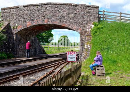 Eine Frau mittleren Alters wartet auf einen Zug am Irton Road Station auf der Ravenglass und Eskdale Railway am Eskdale Green Lake District Cumbria England Stockfoto