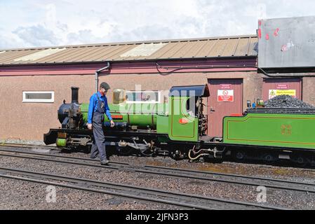 Ein Motorfahrer an der River IRT Dampflokomotive am Bahnhof Ravenglass auf der historischen Eisenbahn Cumbria England UK Stockfoto