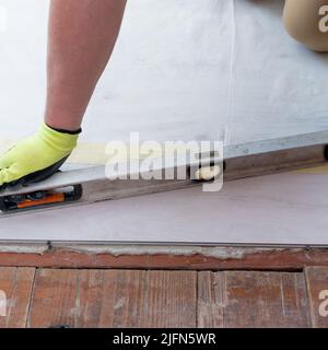 Der Master misst die Höhe der Bodenfläche, Reparatur- und Installationsarbeiten. Stockfoto