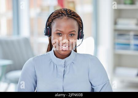 Porträt einer lächelnden afroamerikanischen Geschäftsfrau, die ein Headset mit Mikrofon trägt. Der Kundendienstmitarbeiter sieht im Büro positiv aus Stockfoto