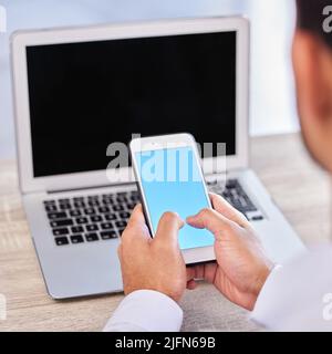 Nahaufnahme Hand des Geschäftsmannes mit Smartphone. Geschäftsmann tippen auf blauen leeren Bildschirm Handy-Mockup und Surfen im Internet auf Laptop. Verknüpfung Stockfoto