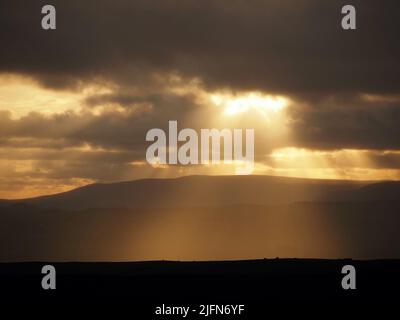 Abends brechen goldene Sonnenstrahlen durch Wolkenufer über der Landschaft der Pennine Hills in North Yorkshire, England, Großbritannien Stockfoto