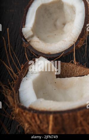 Gehackte Kokosnuss auf einem hölzernen Hintergrund, Draufsicht. Kokosmilch und Kokosflocken sind tropische Lebensmittel Stockfoto