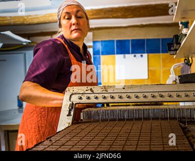 Mitarbeiter der Chocolaterie Frigoulette in Beaufort-sur-Gervanne (die, Frankreich) beim Schneiden von Nougatpralinen. Die, Frankreich Stockfoto