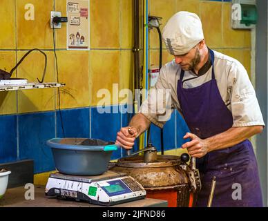 Ein Angestellter der Chocolaterie Frigoulette schließt den Mélangeur, in dem die gewogenen Marschmarrogen gemischt und erhitzt werden. Frigoulette verwendet keine tierischen Fette wie Milch, Rahm oder Butter. Palmöl wird ebenfalls nicht verwendet. Stattdessen 68 Prozent Kakao und echte Kakaobutter aus São Tomé Stockfoto