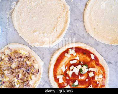 Hintergrundbild von einigen Pizzen auf Marmorplatte mit Mehl und traditionellen italienischen Zutaten, traditionelle neapolitanische Pizza Stockfoto