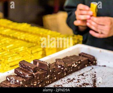 Handgefertigt, ist der Bestseller der Schokoladenmanufaktur Frigoulette in goldenes Papier gewickelt. Die Malakoff-Praline aus der Chocolaterie Frigoulette ist in ganz Frankreich erhältlich und besonders zu Weihnachten beliebt. Malakoff ist eine dieser in Scheiben geschnittenen Pralinen, die keine zusätzliche Verpackung in der Mitte haben. Die gerösteten Haselnüsse verleihen der Praline eine knusprige Textur Stockfoto