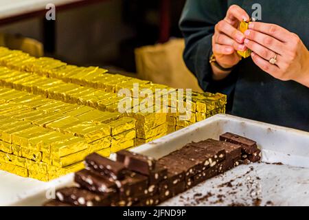 Handgefertigt, ist der Bestseller der Schokoladenmanufaktur Frigoulette in goldenes Papier gewickelt. Die Malakoff-Praline aus der Chocolaterie Frigoulette ist in ganz Frankreich erhältlich und besonders zu Weihnachten beliebt. Malakoff ist eine dieser in Scheiben geschnittenen Pralinen, die keine zusätzliche Verpackung in der Mitte haben. Die gerösteten Haselnüsse verleihen der Praline eine knusprige Textur Stockfoto